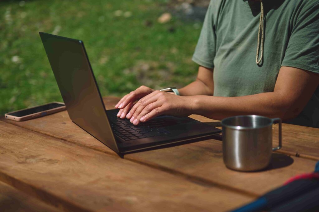 A woman working on a table with her laptop. - Is a Virtual Assistant Worth It for a Travel Blogger?